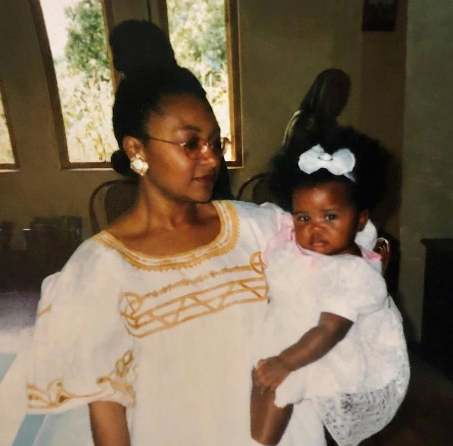 Maureen Tufon holidng a toddler Dedra Tufon Bauer dressed in tradiitonal Cameroonian attire